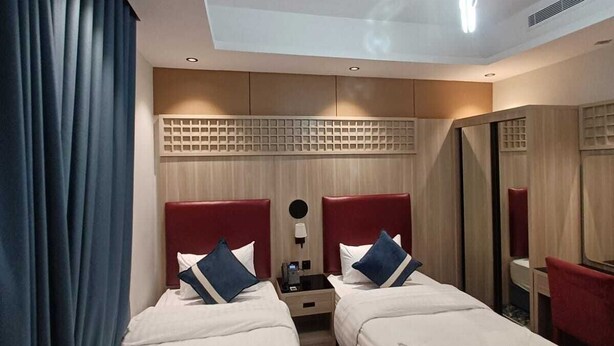 Habitació d'hotel amb dos llits, una taula de nit, un mirall i una làmpada al sostre.