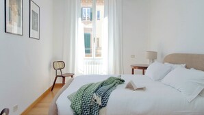 Een slaapkamer met een bed, een stoel, een lamp en een raam.