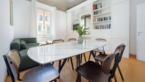 Een eetgedeelte met een ronde tafel, stoelen, een bank en een boekenkast.