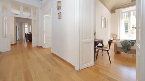 Een ruime kamer met houten vloeren, witte muren en een eethoek met een tafel en stoelen.