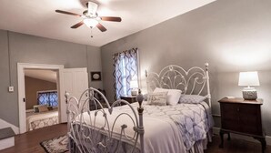 A bedroom with a bed, a ceiling fan, a nightstand, and a window with curtains. - Armory Quarters B (Bolivar)