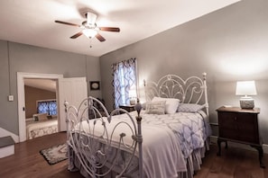 A bedroom with a bed, a ceiling fan, a nightstand, and a window with curtains.