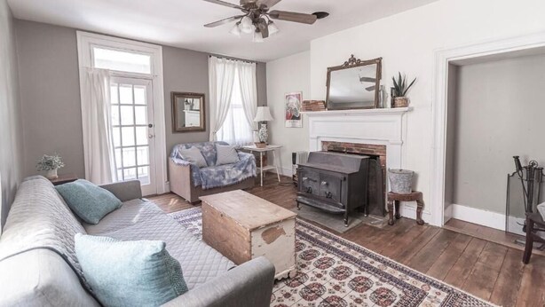 A living room with a sofa, a fireplace, a ceiling fan, and a window with curtains. - Armory Quarters B (Bolivar)