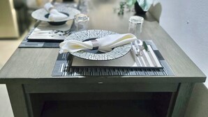 A dining table set with plates, cutlery, and napkins, with a plant and a glass on the table. - Cozy 2 Bedroom Flat W Pool/ Free Parking (Philipsburg)