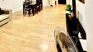 Un grand espace de vie comprenant une table à manger, des chaises, un canapé, un téléviseur et un ventilateur.