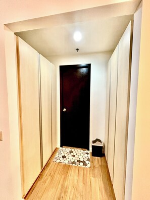 A narrow hallway with a wooden floor, a black door, and a small step leading to a tiled area. - Condo In Abreeza  Family and Spacious (Davao City)