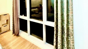 Une pièce avec une grande fenêtre, un plancher en bois et un rideau.