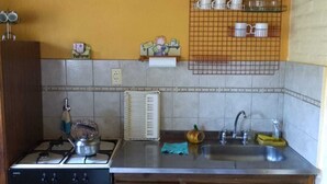 Une cuisine avec des meubles en bois, une cuisinière, un évier et un pare-feu en carreaux.