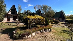 Une rangée de charmantes maisons en pierre aux toits verts, entourées de jardins bien entretenus et sous un ciel bleu azur.