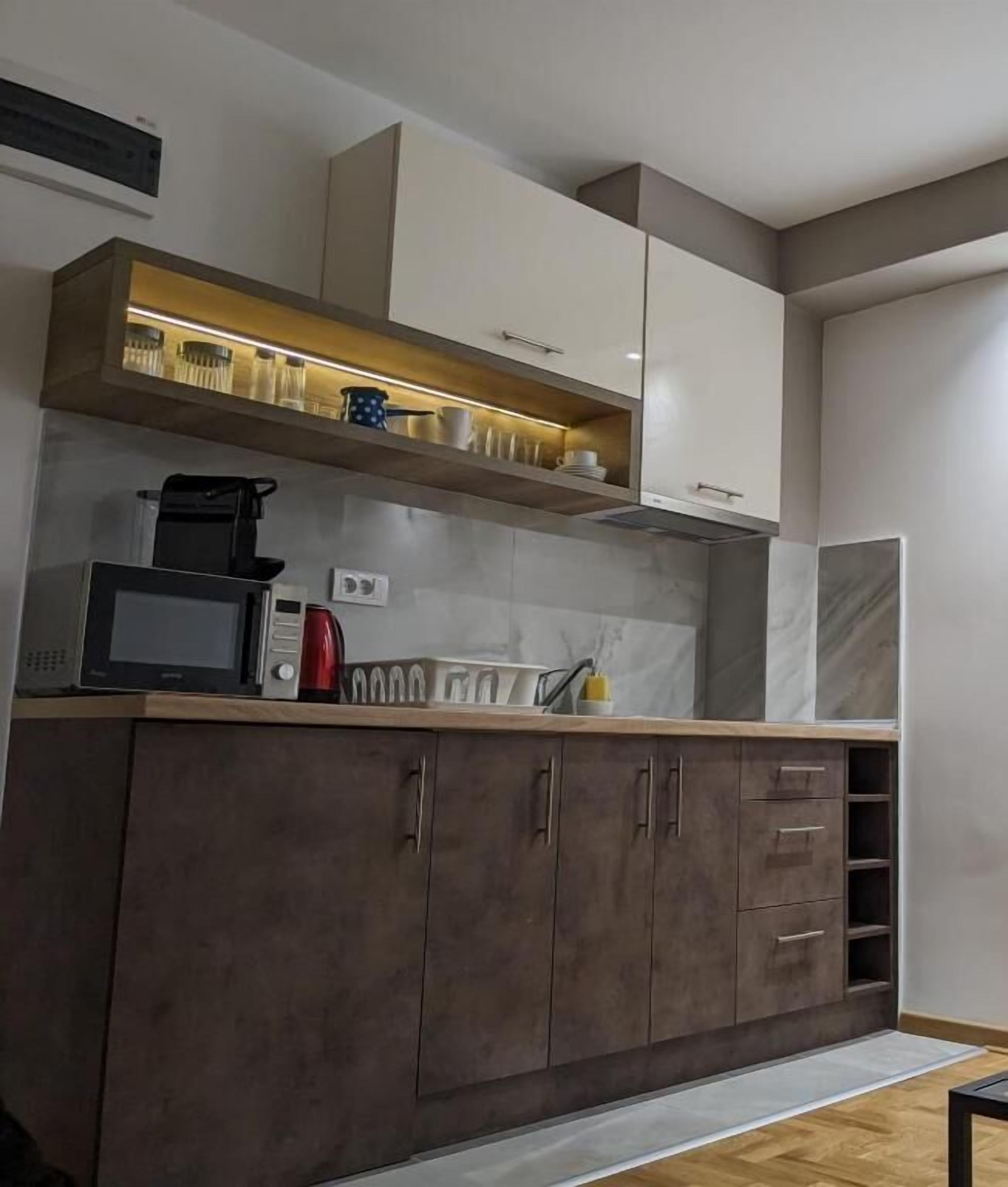 A modern kitchen with a microwave, coffee maker, and cabinets.
