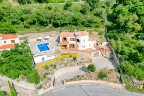 Vue aérienne d’une propriété dotée d’une piscine, d’un bâtiment circulaire et d’un espace verdoyant environnant.
