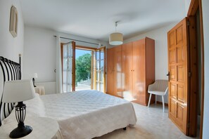 Une chambre à coucher avec un lit, une chaise, une armoire et une fenêtre avec des rideaux.
