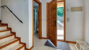 Uma escada leva a um banheiro com chuveiro, uma porta de madeira e um tapete pequeno na entrada.