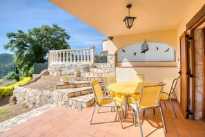 Une terrasse avec une table et des chaises, un escalier en pierre et une vue sur le paysage.