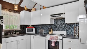 Une cuisine moderne avec des meubles blancs, un four à micro-ondes, un grille-pain et une cuisinière.