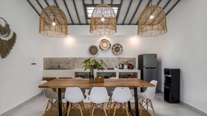 Eine moderne Küche mit Holztisch, weißen Stühlen, einer Pendelleuchte und einem eingebauten Backofen.