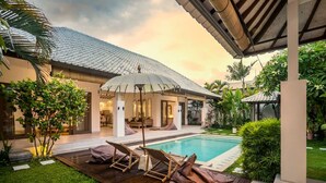 Ein Poolbereich mit Liegestühlen und einer überdachten Lounge-Ecke.
