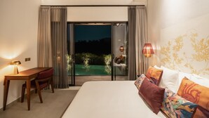 Ein Schlafzimmer mit Bett, Schreibtisch und Blick auf einen Pool bei Nacht.