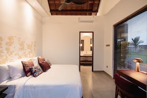Ein Schlafzimmer mit Bett, Schreibtisch, Stuhl, Deckenventilator und einem Fenster mit Jalousien.