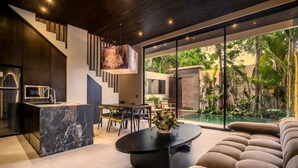 Un intérieur moderne comprenant une cuisine, un coin repas et une grande fenêtre donnant sur un jardin.