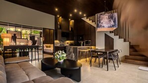 Un intérieur moderne comprenant un canapé, un coin repas, une cuisine et un escalier.