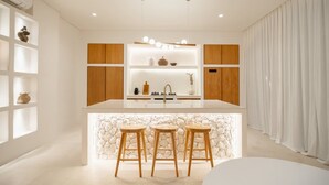 Een moderne keuken met een centraal eiland, houten kasten en een accentmuur van steen.