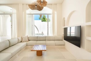 A modern living room with a large sectional sofa, a wooden coffee table, and a flat-screen TV mounted on the wall. - Tomar El Sol in South Kuta (South Kuta)