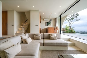 Ein modernes Wohnzimmer mit einer Couch, einem Essbereich und einer Treppe.