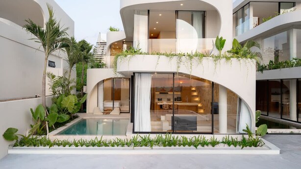 A modern multi-story building with a pool, outdoor seating, and lush greenery. - Villa Ohana in South Kuta (South Kuta)