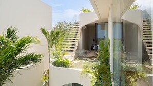 A modern building with a glass facade, outdoor greenery, and a staircase leading to an upper level. - Villa Ohana in South Kuta (South Kuta)