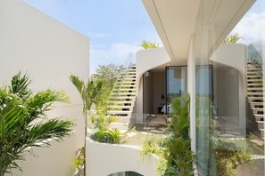 A modern building with a glass facade, outdoor greenery, and a staircase leading to an upper level. - Villa Ohana in South Kuta (South Kuta)