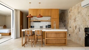 A modern kitchen with wooden cabinets, pendant lights, and a central island with bar stools. - Villa Ohana in South Kuta (South Kuta)