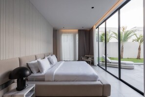 A modern hotel room with a large bed, a desk, and a view of the outdoors. - Villa Sayuri in Kecamatan Kuta Utara (Kecamatan Kuta Utara)