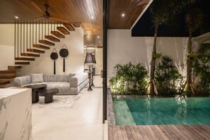 A modern interior with a staircase, a pool, and a living area with a sofa and coffee table. - Rocca Bella Loft 1 in Canggu (Canggu)