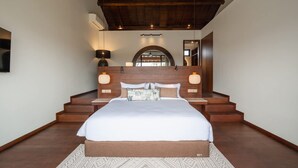 A bedroom with a large bed, wooden headboard, two bedside lamps, and a ceiling fan. - Rocca Bella Loft 1 in Canggu (Canggu)