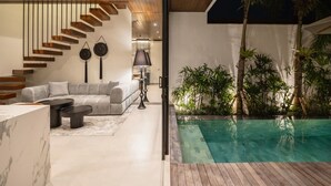 Ein modernes Interieur mit einer Treppe, einem Pool und einem Wohnbereich inklusive Sofa und Couchtisch.