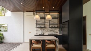 Eine moderne Küche mit Marmorfliesenspiegel, zwei Pendelleuchten und einem schwarzen Kühlschrank.
