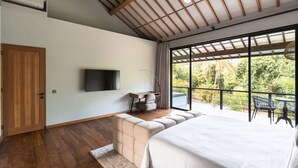 Quarto com cama grande, televisão, escrivaninha e varanda com área de estar externa.