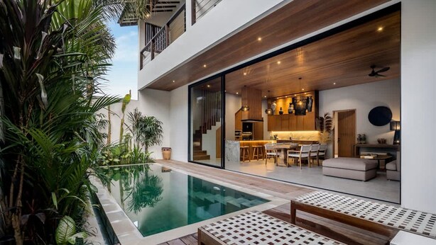 Een modern huis met een zwembad, houten terras en een keuken met een eethoek.