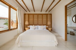A bedroom with a large bed, wooden headboard, two bedside lamps, a window with curtains, and a view of the outdoors. - Mr    Mrs  W Bingin in Kecamatan Kuta Selatan (Kecamatan Kuta Selatan)