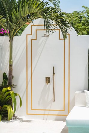 A white wall with a gold outline, a shower, and a small plant. - Villa Mauka in Canggu (Canggu)