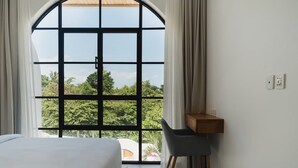 Ein Schlafzimmer mit großem Fenster, einem Bett, einem Schreibtisch und einem Stuhl.