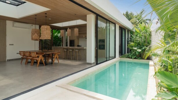 Een modern huis met een zwembad, eethoek en keuken.