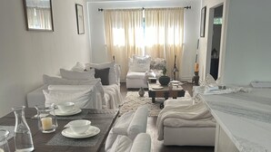Habitación de hotel con comedor, sofá, cama y vistas al exterior.