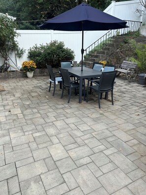 An outdoor patio with a table and chairs, a potted plant, and a staircase. - Charming 3-bedroom house in Yonkers with cool vibes and AC (Yonkers)