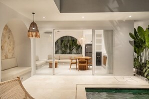 A modern interior with a pool, a dining area, and a living room with a sofa and chairs. - Villa Paraiso in Bingin Beach (Bingin Beach)