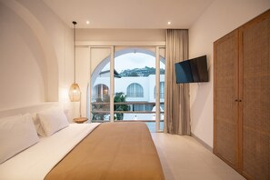 A bedroom with a bed, a TV mounted on the wall, and a large window with a view of buildings. - Villa Paraiso in Bingin Beach (Bingin Beach)