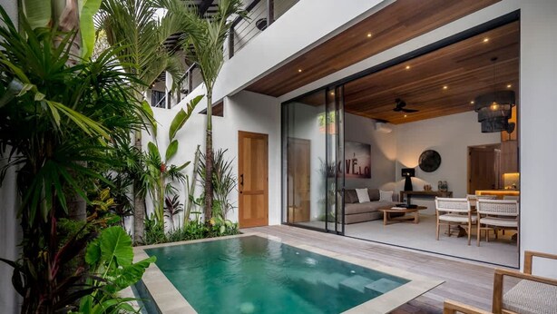 Ein modernes Haus mit Swimmingpool, Holzterrasse und einer gemütlichen Sitzgelegenheit im Innenbereich.