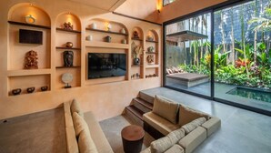 Ein modernes Wohnzimmer mit einer Couch, einem Fernseher und Regalen mit Dekoration.