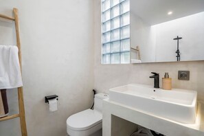 A modern bathroom with a white sink, toilet, and a wooden ladder. - Casa Copper in Kecamatan Mengwi (Kecamatan Mengwi)